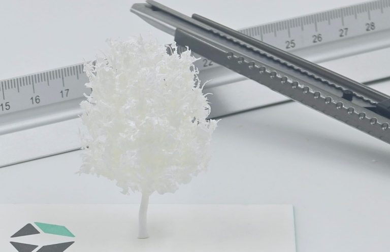 Weiße Baum-Skulptur aus Kunststoff, neben einem Lineal auf einem Tisch platziert.